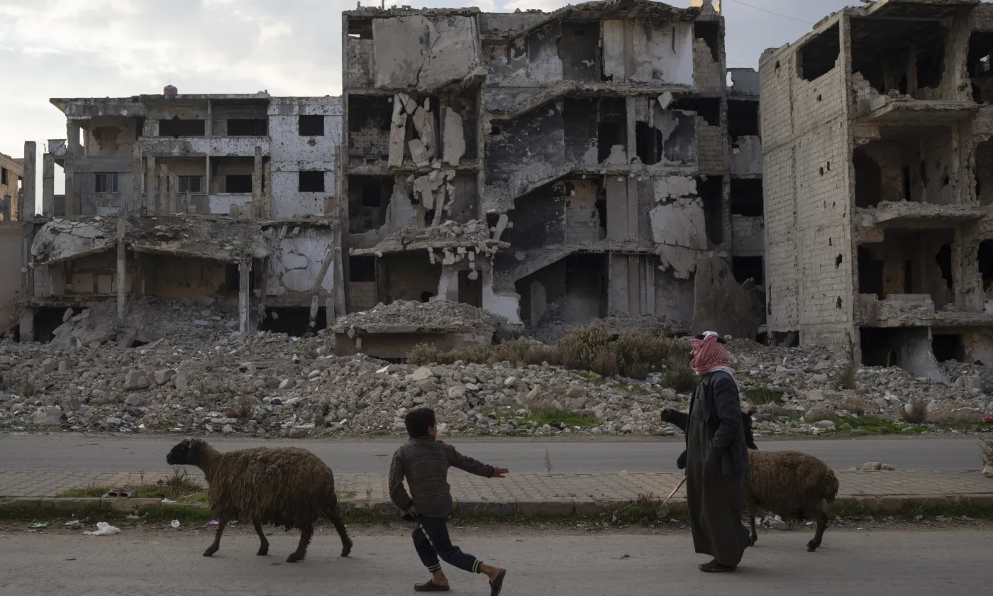 Un enfant court après les moutons en passant devant des bâtiments détruits pendant la guerre civile dans le quartier de Khalidiya à Homs, en Syrie, mercredi 1er janvier 2025. Keystone